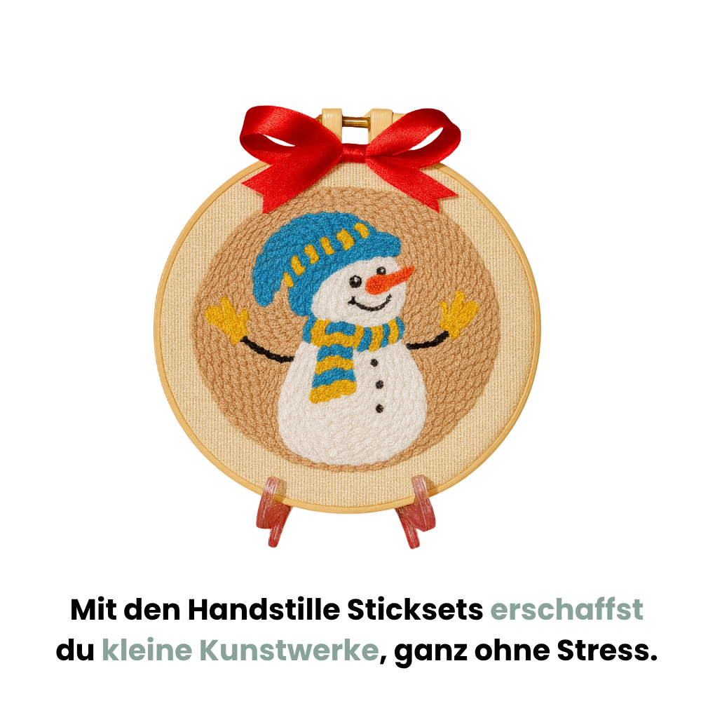Punch Needle Wintermotiv mit Schneemann und roter Schleife im Stickrahmen, Text: ‚Mit den Handstille Sticksets erschaffst du kleine Kunstwerke, ganz ohne Stress.‘ Kreatives Punch Needle Set für Anfänger und DIY-Winterdeko